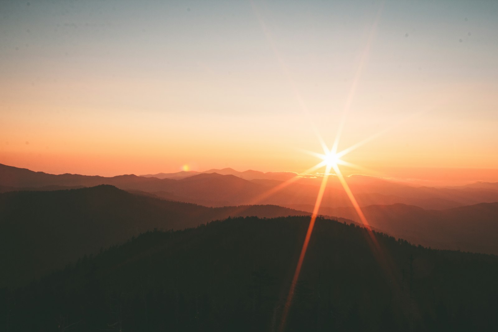 Sol poniéndose detrás de montañas